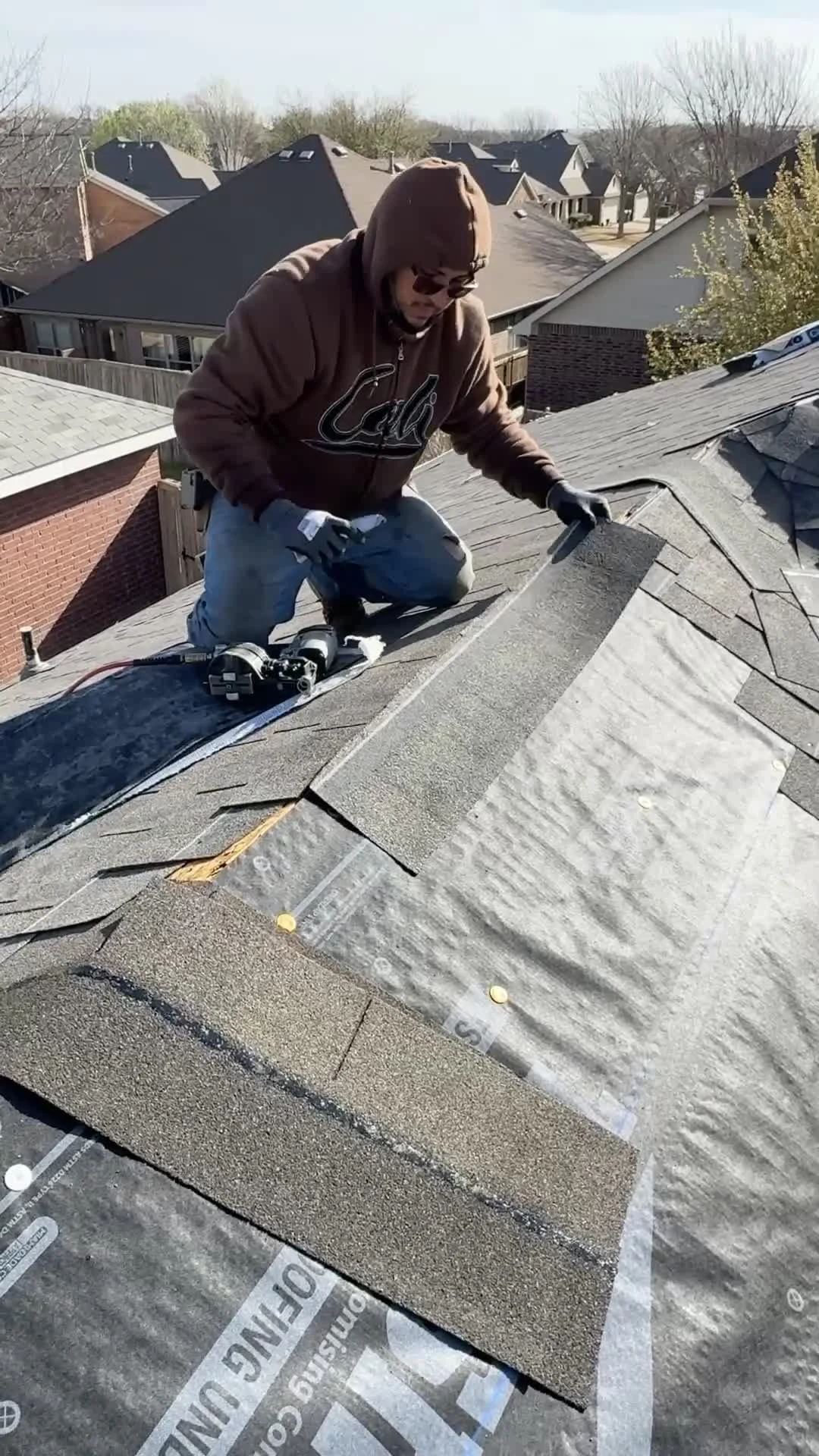 Frame Restoration roof repair detail work in McKinney, Texas, showing a worker setting shingles beside exposed underlayment