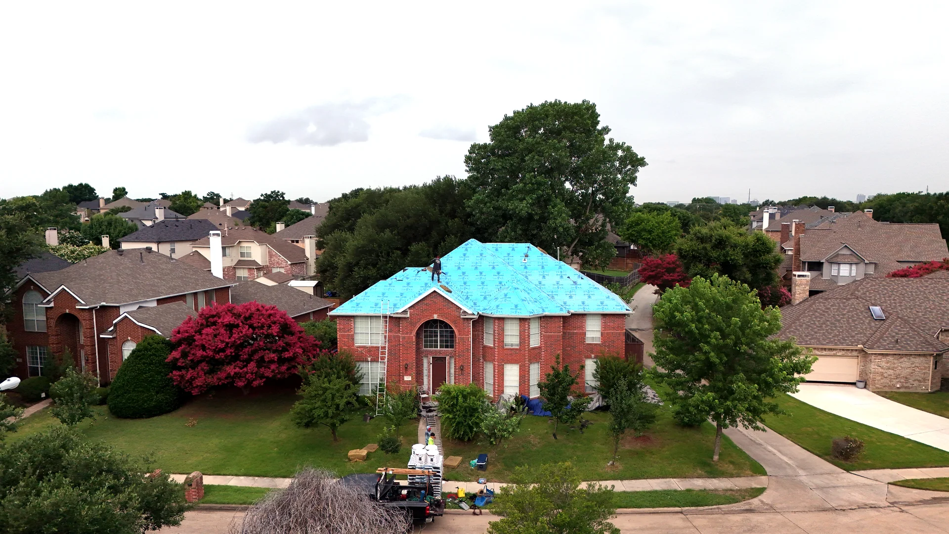 Drone photograph of a Plano roof underlayment installation in progress, with surrounding North Texas homes visible
