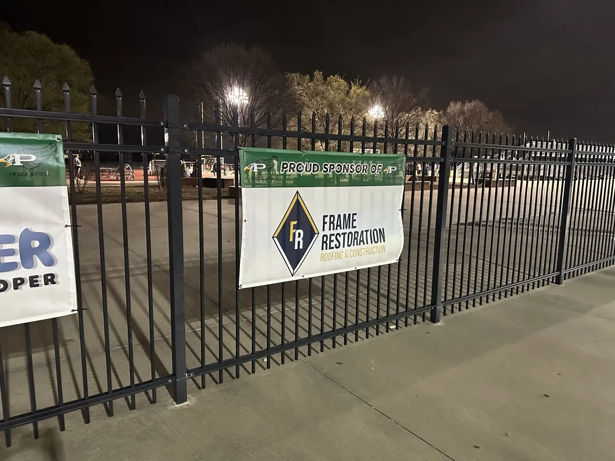 Frame Restoration sponsor banner on a Prosper High School fence at night